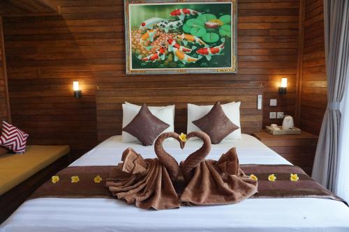twee handdoezwanen zittend op een bed in een kamer bij Singabu Bungalows in Nusa Penida