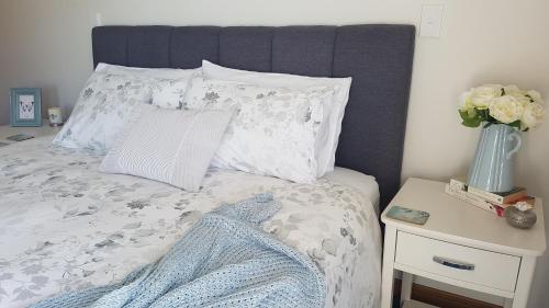 a bed with a pillow and a vase with flowers at Above the River Karapiro Bed & Breakfast in Karapiro
