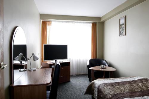 a hotel room with a bed and a desk and a television at Hotel Šiauliai in Šiauliai