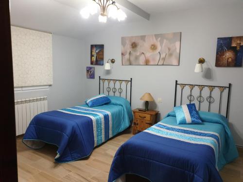 two beds in a room with blue comforters at Maitemare in Traspinedo