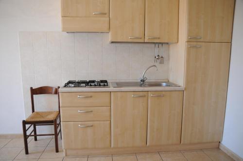 a kitchen with wooden cabinets and a sink and a chair at Villa Grazia in Capo Vaticano