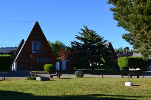 a church with a grassy yard with a bench in front at Cabañas Nevis, excelente ubicación in El Calafate