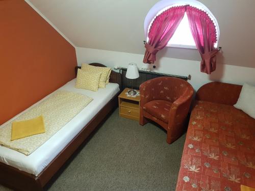a small bedroom with a bed and a chair at Duna Panzió in Győr