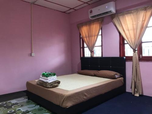 a bedroom with a bed with pink walls and windows at langkawi homestay murah in Kuah