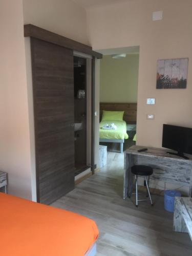 a bedroom with a bed and a desk with a television at Locanda Ponte Rosa in Garessio