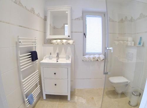 a white bathroom with a sink and a toilet at Gästhuus - Urlaub aan de Ostsee in Timmendorfer Strand