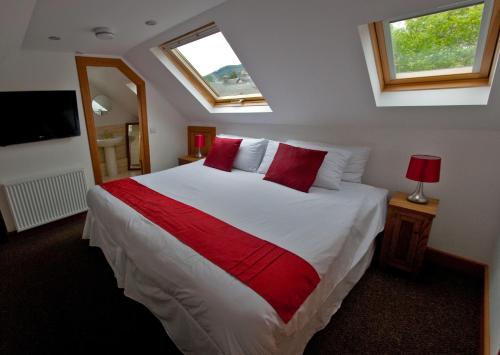 una camera da letto con un grande letto bianco con cuscini rossi di Lugonia a Pitlochry