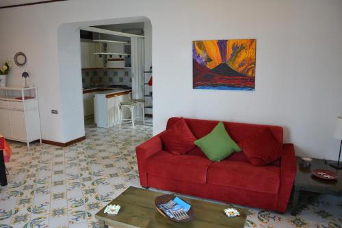 a living room with a red couch and a kitchen at Le Cicale - Apartments in Conca dei Marini