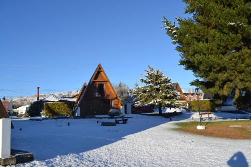 a church with a snow covered yard with a building at Cabañas Nevis, excelente ubicación in El Calafate