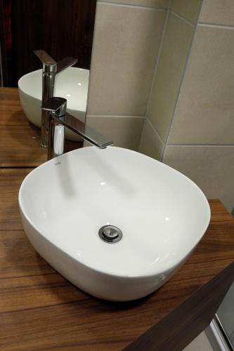 a white sink on a wooden counter in a bathroom at Vácz Hotel in Vác