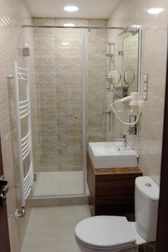 a bathroom with a shower and a toilet and a sink at Vácz Hotel in Vác