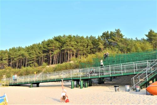 Una mujer parada en la playa al lado de un puente en Apartamenty Gabrysia 8, en Międzywodzie