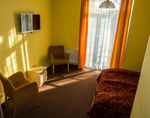 a bedroom with a bed and a chair and a tv at Hotel Vilmaja in Riga