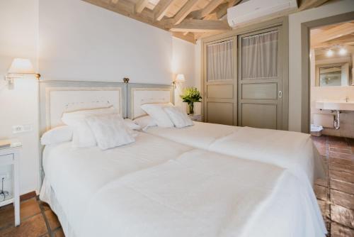 a large white bed with white sheets and pillows at Palacio De Los Navas in Granada