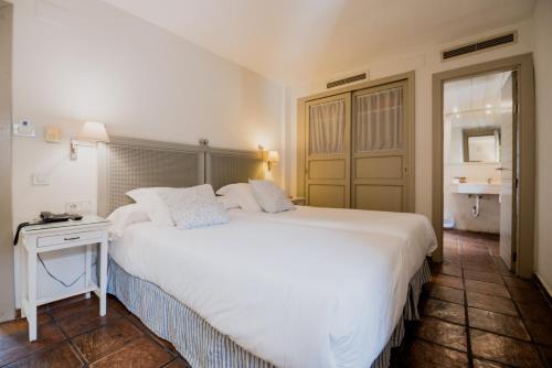 a bedroom with a large white bed and a table at Palacio De Los Navas in Granada