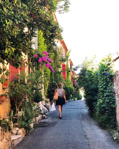 a woman walking down a street with flowers at Hotel Le Ponteil in Antibes