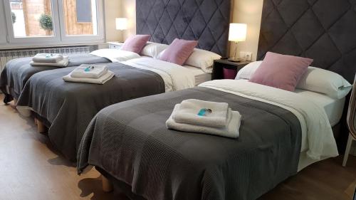 two beds with towels on top of them in a room at PortoHouse in Portomarin
