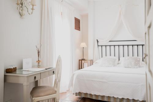 a white bedroom with a white bed and a desk at Palacio De Los Navas in Granada