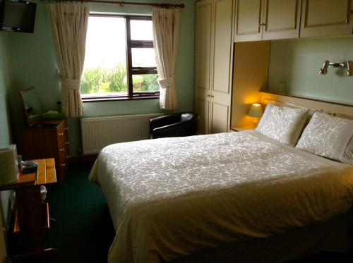 um quarto com uma cama branca e uma janela em Cnoc Breac B&B em Cleggan