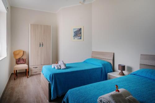 ヴィーコ・エクエンセにあるCasa Florianaのベッドルーム1室(青いシーツと椅子付きのベッド2台付)