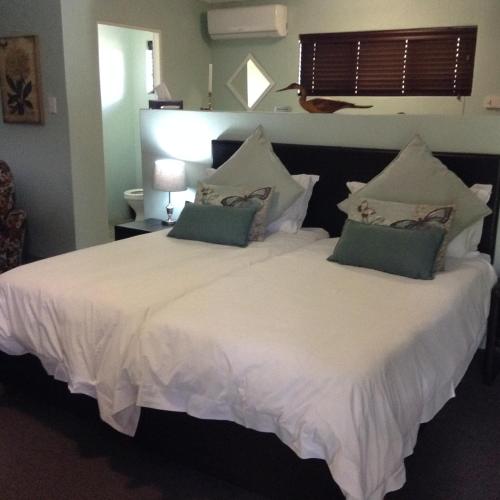 a bedroom with two beds with white sheets and green pillows at Gerald's Gift Guest House in Addo