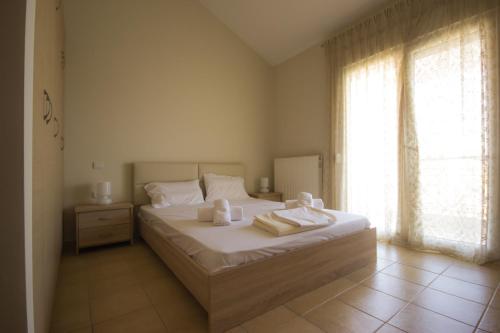 a bedroom with a bed with white sheets and a window at Stasa Luxury Apartments in Keramoti