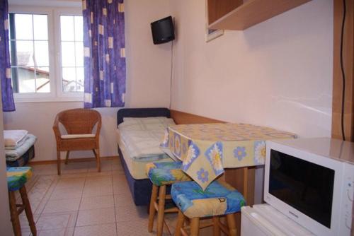 Habitación pequeña con cama, mesa y TV. en Helena, en Karwia