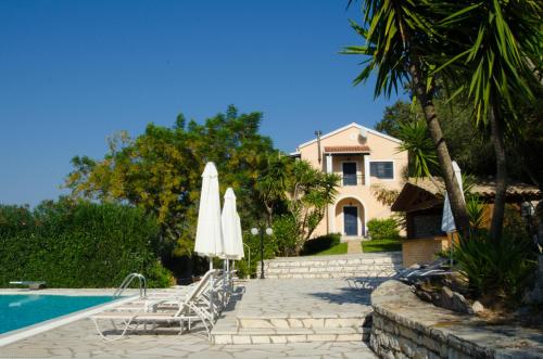 een zwembad met stoelen en parasols naast een huis bij Natural Blue Green Apartment in Almiros strand