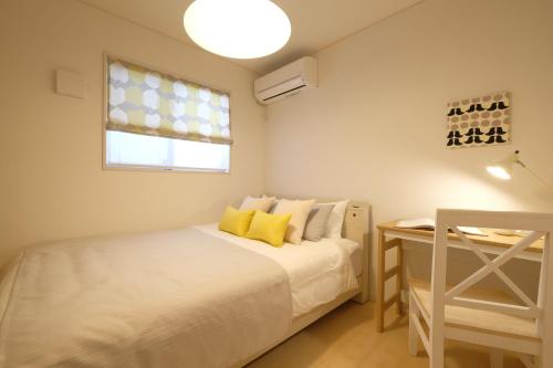 1 dormitorio con cama, ventana y escritorio en Bremen House ~ブレーメンハウス~, en Yomitan