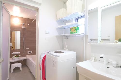 un baño blanco con lavadora y secadora. en Bremen House ~ブレーメンハウス~, en Yomitan