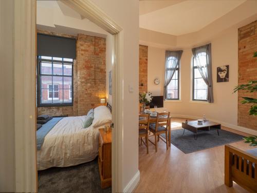 a bedroom with a bed and a dining room with a table at Apartment 16 Broadway House in Nottingham