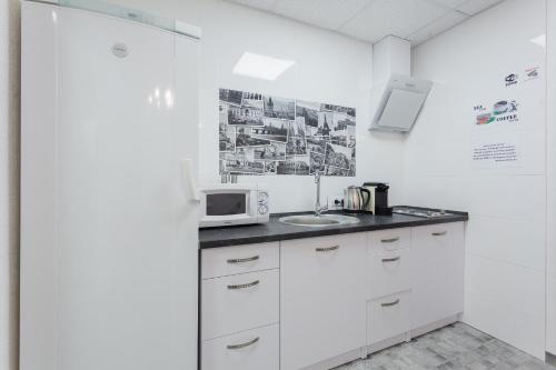 a white kitchen with a sink and a microwave at SkyHome na Nauky in Kyiv