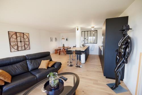 a living room with a black couch and a kitchen at Jean Bart - proximité centre - 2 chambres 90 m2 avec jardin in Saint-Brieuc