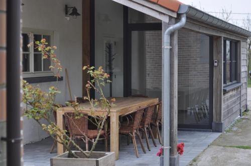 a wooden table and chairs on a patio at Wilgenwind in Sijsele