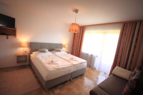 フューゲンベルクにあるHotel Pension Eichenhofのベッドルーム(ベッド1台、ソファ付)