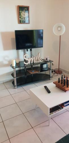 uma sala de estar com uma televisão e uma mesa com um tabuleiro de xadrez em T2 confort et chaleureux (bienvenue chez zot) em La Marine