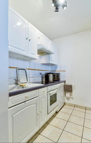 a kitchen with white cabinets and a stove top oven at Le Contemporain in Montbéliard