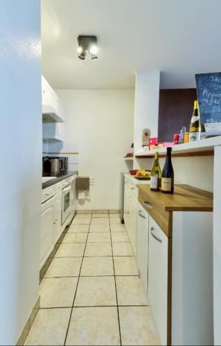 a kitchen with white cabinets and a tiled floor at Le Contemporain in Montbéliard