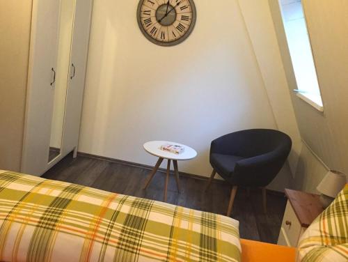 ein Zimmer mit einem Stuhl und einer Uhr an der Wand in der Unterkunft Ferienwohnung Hotel Glockenhof in Eltville