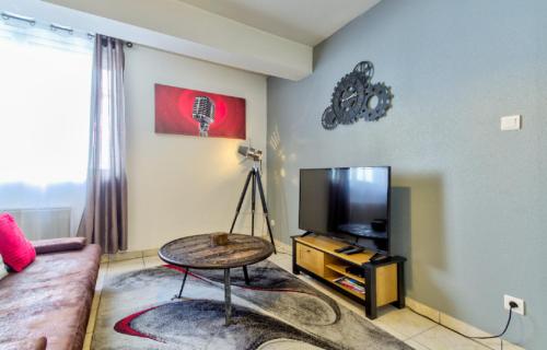 a living room with a couch and a flat screen tv at Le Contemporain in Montbéliard