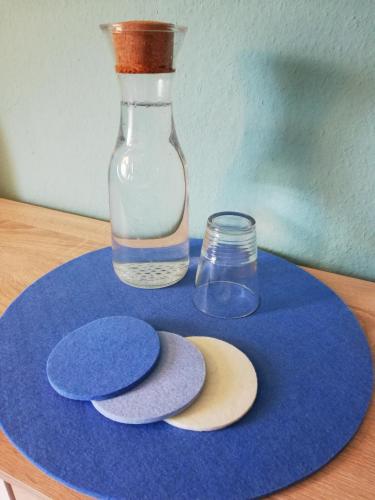 eine blaue Platte mit einer Glasvase und einigen Steinen in der Unterkunft Gästezimmer am Deister in Springe