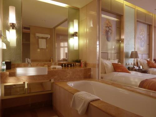 a bathroom with a bath tub and a bed at Wenjin Hotel, Beijing in Beijing