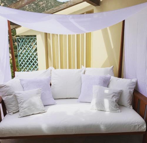 a white bed with white pillows on a porch at Villa Sardinia Seaview&SPApool in Villasimius