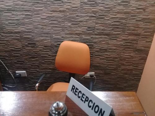 an orange chair in an office with a registration sign at Dennisse Hotel in Victoria