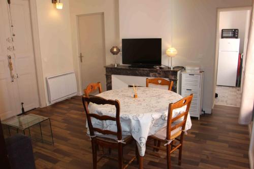 a dining room with a table and chairs and a television at Superbe T2 3 étoiles à proximité des thermes et des pistes cyclables in Lamalou-les-Bains