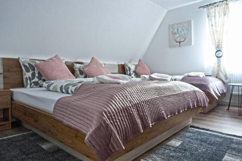 a bedroom with a large wooden bed with pink pillows at Hotel Zum Böhmegrund in Bad Fallingbostel