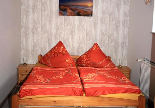ein Bett mit roten Kissen darüber in der Unterkunft Ferienwohnung Sundhagen in Reinberg