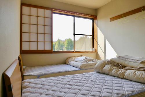 um quarto com duas camas e uma grande janela em FWA Guest House em Fujinomiya