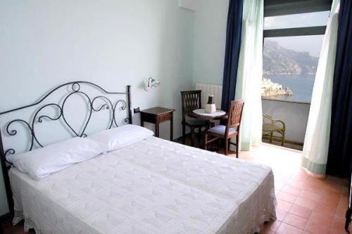 um quarto com uma grande cama branca e uma varanda em Villa Rina em Amalfi