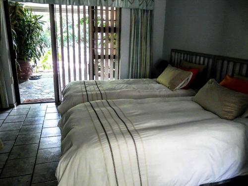 a bedroom with two beds and a sliding glass door at Africa's Eden Guesthouse in Pietermaritzburg